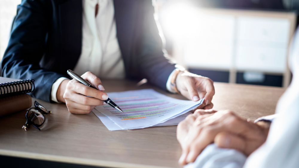 A financial advisor in a suit sits at a desk, reviewing a legal document.