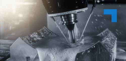 A CNC milling machine actively cuts a metallic workpiece, with coolant fluid spraying to manage heat and clear debris. The rotating cutting tool engages the metal, producing foam and fluid splashes. The setup suggests high-speed, precision machining in an industrial setting.