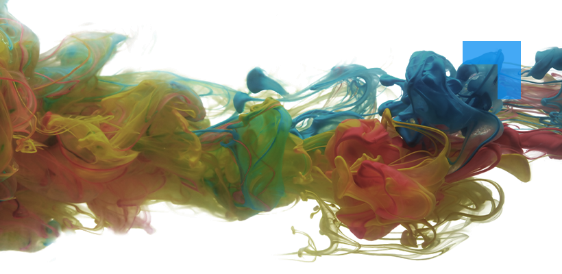 A vivid abstract image showing clouds of colored ink — yellow, green, blue, and red — swirling and merging together in water against a bright white background. The colors form soft, fluid tendrils and waves that intertwine, creating a dynamic sense of motion and blending.