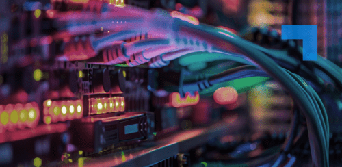 Close-up of colourful network cables and blinking server lights inside a data centre rack, showing a tangle of connected wires and glowing equipment.