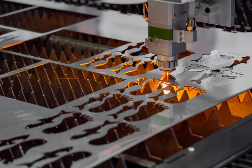 Laser cutting machine cutting precision metal components in an engineering manufacturing facility