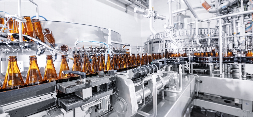 image of brown glass bottles on top of machinery in a food or beverage factory 