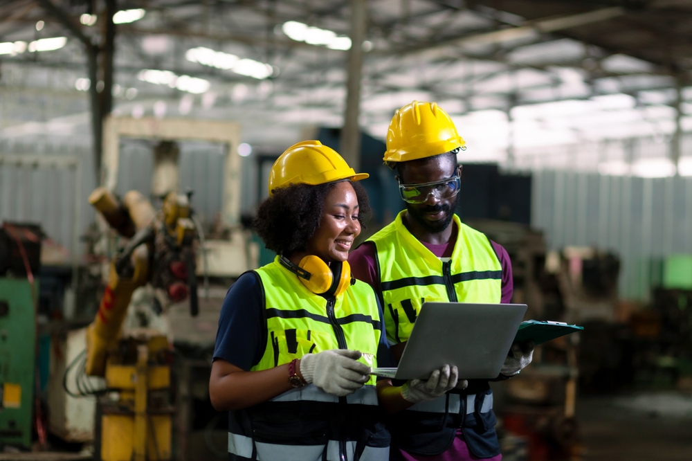 Manufacturing professionals reviewing production data on a laptop in an industrial facility