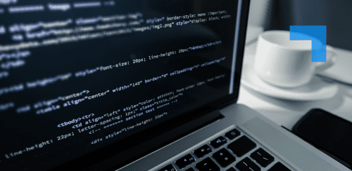 Close-up of a laptop displaying lines of code, with a coffee cup and smartphone on a desk beside it.
