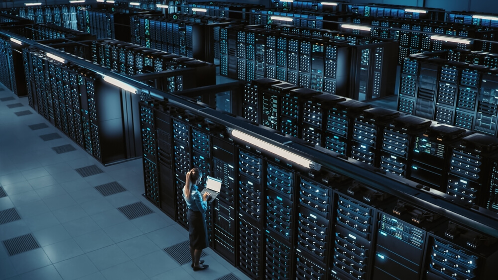 selling my saas business image of business woman holding laptop in front of servers
