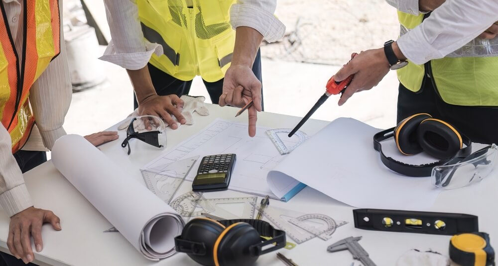 construction co-workers in high-vis jackets collaborating around a table on-site