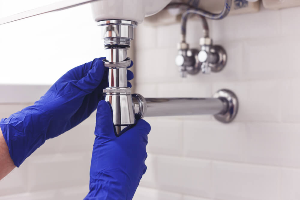 close up image of a plumber's hands working on a sink