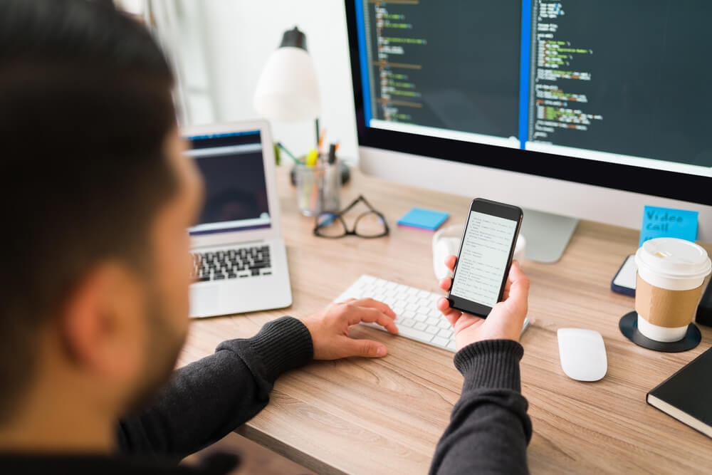 image of a male worker at a software company using mobile phone at desk