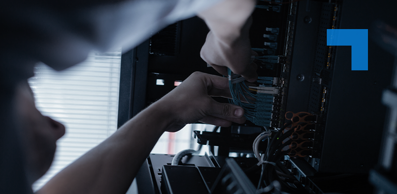 A technician connecting network cables to IT infrastructure in a server cabinet.