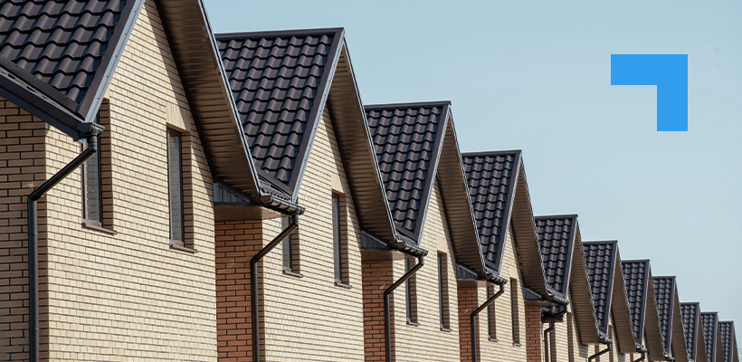 A row of new-build residential houses with dark tiled roofs and brick facades.